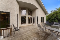 Exterior stucco finish, prominent gabled roofline, expansive wood deck, multiple large windows, and a glass-paneled entry door - 