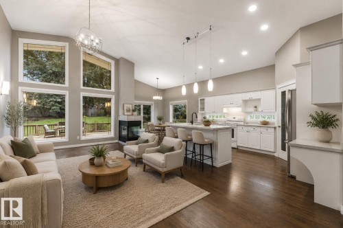 Vaulted ceilings, dark wood-finish flooring, white kitchen cabinetry with a central island, recessed lighting, and a built-in fireplace - 8 Osborne Close, St. Albert, AB - Indoor Photo Showing Living Room
