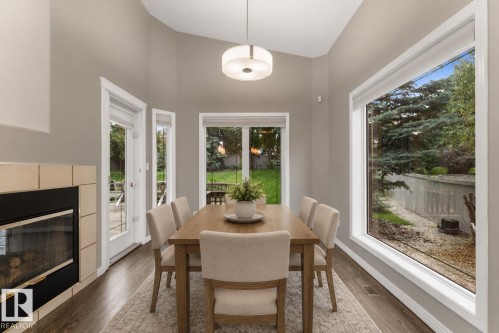 Vaulted ceilings, a fireplace with a tile surround, wood-finish flooring, and multiple windows, including a large picture window - 8 Osborne Close, St. Albert, AB - Indoor Photo Showing Dining Room With Fireplace