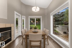 Vaulted ceilings, a fireplace with a tile surround, wood-finish flooring, and multiple windows, including a large picture window - 