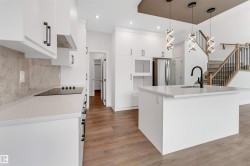Modern kitchen featuring white cabinetry, stone countertops, and wood-finish flooring - 