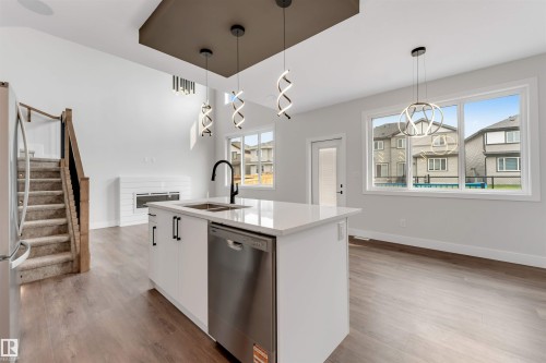 Modern kitchen island with a white countertop, undermount sink with a matte black faucet, and integrated stainless steel dishwasher - 329 Balsam Link, Leduc, AB - Indoor Photo Showing Kitchen With Double Sink With Upgraded Kitchen