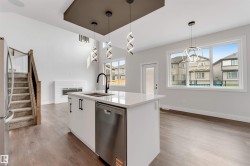 Modern kitchen island with a white countertop, undermount sink with a matte black faucet, and integrated stainless steel dishwasher - 
