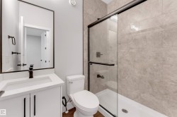 Bathroom featuring a modern vanity with integrated sink and quartz-finish countertop, black-framed mirror, and a glass-enclosed shower with subway tile surround and dark bronze hardware - 