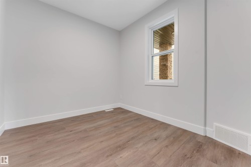 Room featuring wood-finish flooring, light grey painted walls, white baseboards, and a white-framed window - 329 Balsam Link, Leduc, AB - Indoor Photo Showing Other Room