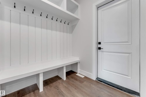 Custom built-in hall tree featuring a white board and batten back panel, a long bench, upper shelving, and multiple black coat hooks - 329 Balsam Link, Leduc, AB - Indoor Photo Showing Other Room