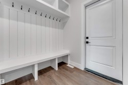 Custom built-in hall tree featuring a white board and batten back panel, a long bench, upper shelving, and multiple black coat hooks - 