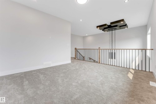 Carpeted loft area featuring a contemporary chandelier, recessed lighting, and a railing system with wood handrails and black metal balusters - 329 Balsam Link, Leduc, AB - Indoor Photo Showing Other Room
