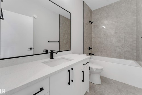 Bathroom featuring a white vanity with an integrated rectangular sink, a white countertop, and matte black fixtures - 329 Balsam Link, Leduc, AB - Indoor Photo Showing Bathroom