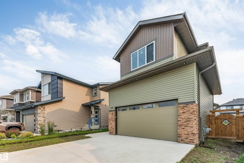 Contemporary two-story exterior featuring a concrete driveway, an integrated single-car garage, and a brown wood fence with an ornate gate - 329 Balsam Link, Leduc, AB - Outdoor