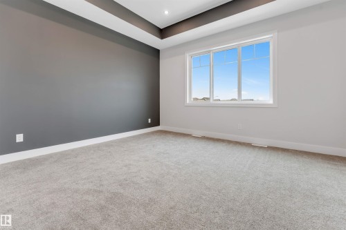 Room featuring a tray ceiling with recessed lighting, large window, gray accent wall, and light gray carpet flooring - 329 Balsam Link, Leduc, AB - Indoor Photo Showing Other Room