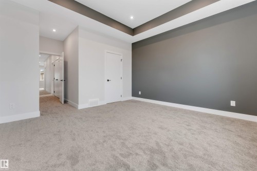 Spacious room featuring plush carpet flooring, a dark accent wall, recessed lighting, and a tray ceiling detail - 329 Balsam Link, Leduc, AB - Indoor Photo Showing Other Room
