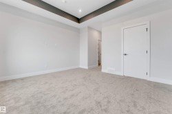 Spacious room featuring plush carpeting, crisp white walls, and a recessed ceiling with dark accent trim - 