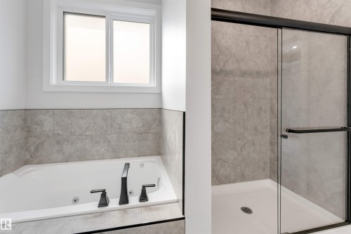 Bathroom featuring a built-in soaking tub with matte black fixtures, a tiled surround, and an overhead window - 329 Balsam Link, Leduc, AB - Indoor Photo Showing Bathroom