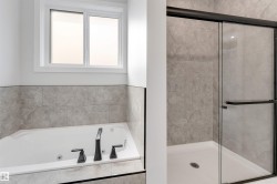 Bathroom featuring a built-in soaking tub with matte black fixtures, a tiled surround, and an overhead window - 
