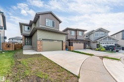 Contemporary two-story residence featuring a two-tone facade, attached front garage, concrete driveway, and a stone accent column - 
