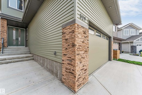 Exterior featuring light green horizontal siding and stacked stone accents - 329 Balsam Link, Leduc, AB - Outdoor
