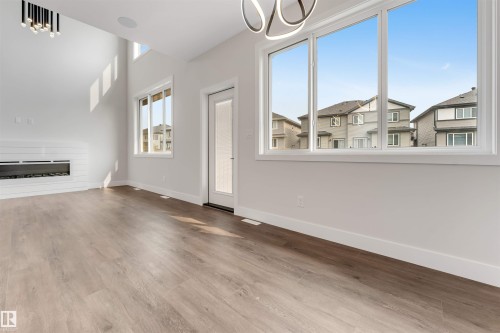 Spacious interior featuring high ceilings, wood-finish flooring, and a modern fireplace with a white shiplap surround - 329 Balsam Link, Leduc, AB - Indoor Photo Showing Other Room