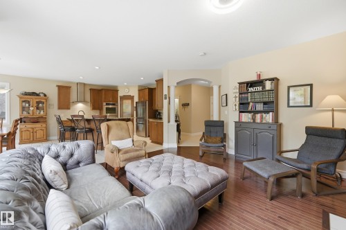 Hardwood flooring, arched doorway, recessed lighting, wood cabinetry, and a kitchen island with bar seating - 2416 Warry Place Sw, Edmonton, AB - Indoor Photo Showing Living Room