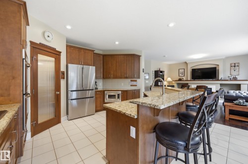 Kitchen featuring wood cabinetry, stainless steel appliances, a center island with bar seating, and recessed lighting - 2416 Warry Place Sw, Edmonton, AB - Indoor Photo Showing Kitchen With Upgraded Kitchen