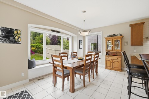 Arched picture window with a built-in window seat, white ceramic tile flooring, neutral wall tones, and a built-in wood hutch - 2416 Warry Place Sw, Edmonton, AB - Indoor Photo Showing Dining Room