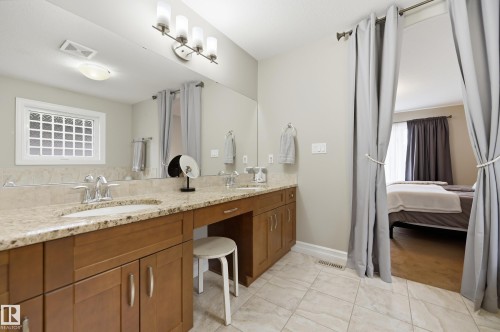 Dual vanity with undermount sinks, granite-look countertop, and wood-finish cabinetry - 2416 Warry Place Sw, Edmonton, AB - Indoor Photo Showing Bathroom