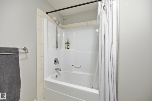 Tub and shower combination with chrome fixtures and integrated shelving - 2416 Warry Place Sw, Edmonton, AB - Indoor Photo Showing Bathroom