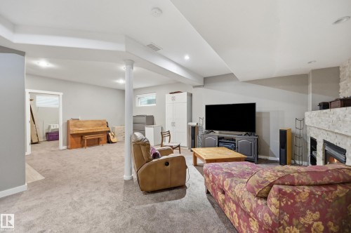 Carpeted lower level with recessed lighting, a stone-clad fireplace, and a white support column - 2416 Warry Place Sw, Edmonton, AB - Indoor With Fireplace