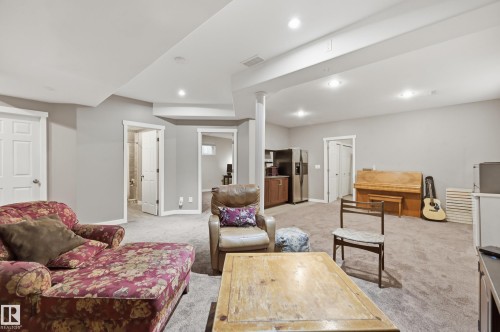 Expansive carpeted area with recessed lighting, multiple doorways, and a built-in wet bar with stainless steel appliances - 2416 Warry Place Sw, Edmonton, AB - Indoor