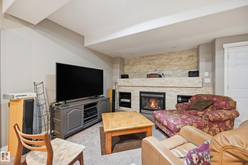 Built-in fireplace with a stone surround, integrated shelving, and carpet flooring - 2416 Warry Place Sw, Edmonton, AB - Indoor Photo Showing Living Room With Fireplace