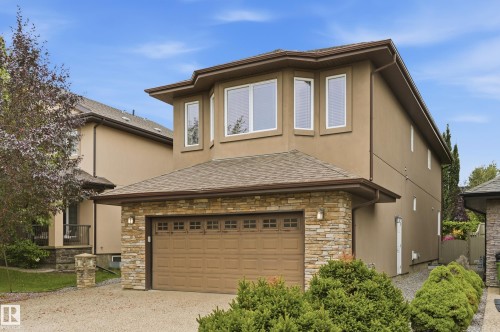 Stucco exterior with stone accents, attached two-car garage, multiple upper-level windows, and a shingled roof - 2416 Warry Place Sw, Edmonton, AB - Outdoor With Exterior