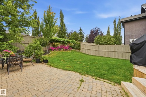 Expansive backyard featuring a paver patio, a manicured lawn, wood fencing, and mature trees - 2416 Warry Place Sw, Edmonton, AB - Outdoor With Backyard