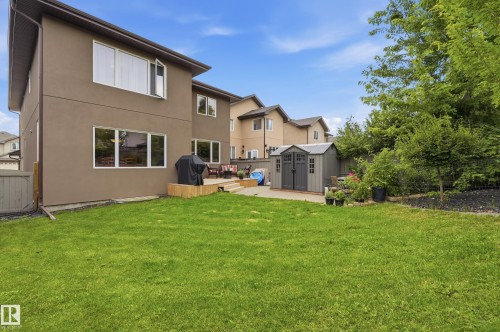 Expansive green lawn, multi-level wood-finish deck, paved patio area, and a grey shed - 2416 Warry Place Sw, Edmonton, AB - Outdoor With Exterior