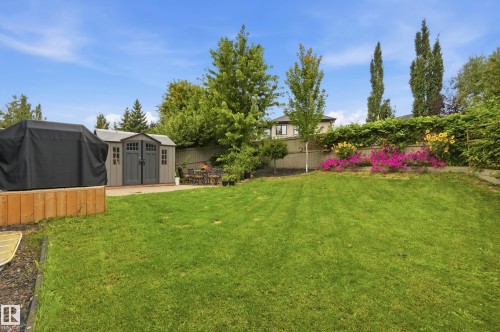 Expansive backyard featuring a manicured lawn, a storage shed, and a paved patio area - 2416 Warry Place Sw, Edmonton, AB - Outdoor