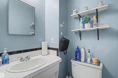 Wall-mounted medicine cabinet, built-in vanity with integrated sink, chrome faucet, tiled backsplash, and dual floating shelves - 5724 143 Avenue Nw, Edmonton, AB - Indoor Photo Showing Bathroom