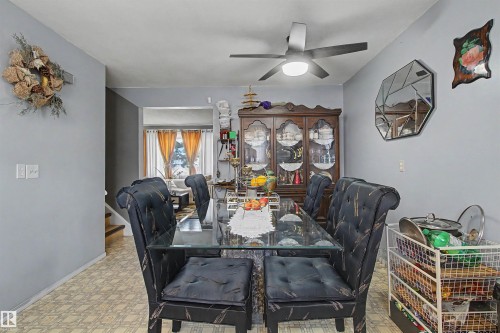 Ceiling fan with integrated lighting, glass top dining table, wood-finish flooring, staircase with wood treads - 5724 143 Avenue Nw, Edmonton, AB - Indoor Photo Showing Dining Room