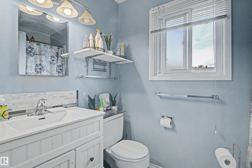 White vanity with beadboard paneling, integrated sink, and chrome-finish faucet - 5724 143 Avenue Nw, Edmonton, AB - Indoor Photo Showing Bathroom