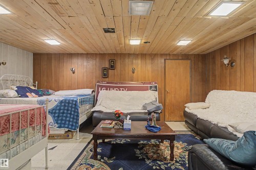 Wood-paneled walls and ceiling, surface-mounted ceiling lights, and wall sconces - 5724 143 Avenue Nw, Edmonton, AB - Indoor Photo Showing Basement