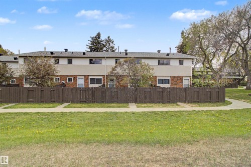 Townhome exterior featuring brick and siding facade, private fenced patio, and individual entry - 5724 143 Avenue Nw, Edmonton, AB - Outdoor