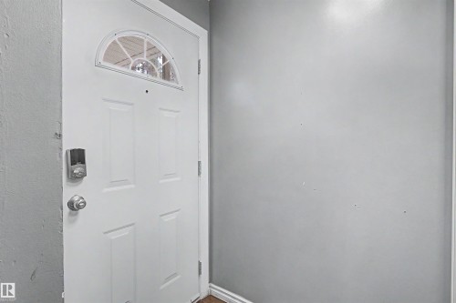 White panel door with an arched transom window and digital entry lock - 5724 143 Avenue Nw, Edmonton, AB - Indoor Photo Showing Other Room