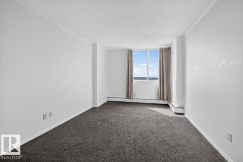 Carpeted flooring, white walls, crown molding, a window with exterior scenery, and baseboard heating - #506 12121 Jasper Av Nw, Edmonton, AB - Indoor Photo Showing Other Room
