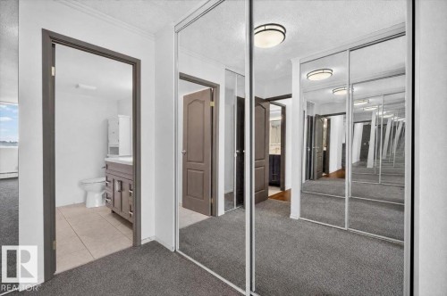 Mirrored closet doors, flush mount ceiling lighting, wood-finish interior doors, and a bathroom with a tile floor - #506 12121 Jasper Av Nw, Edmonton, AB - Indoor Photo Showing Other Room