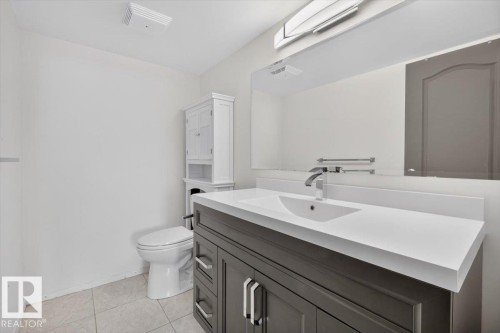 Modern vanity with a sleek countertop and integrated sink, chrome faucet, and expansive mirror - #506 12121 Jasper Av Nw, Edmonton, AB - Indoor Photo Showing Bathroom