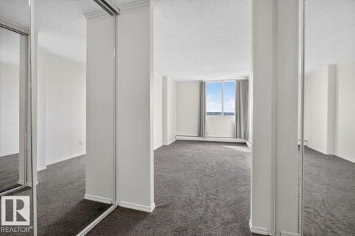 Expansive room with neutral carpeting, large windows, and sliding mirrored closet doors - #506 12121 Jasper Av Nw, Edmonton, AB - Indoor Photo Showing Other Room