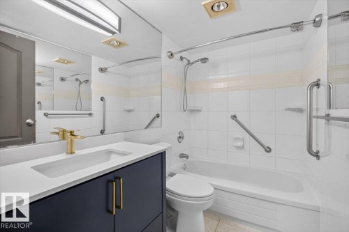 Vanity with integrated sink, brass-finish faucet, and dark cabinetry - #506 12121 Jasper Av Nw, Edmonton, AB - Indoor Photo Showing Bathroom