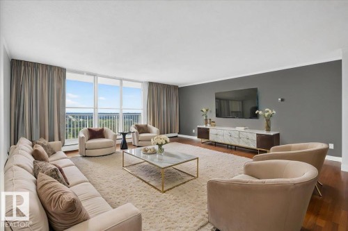 Expansive living area featuring a full wall of windows, hardwood flooring, and a built-in media console with a marble-finish top - #506 12121 Jasper Av Nw, Edmonton, AB - Indoor Photo Showing Living Room