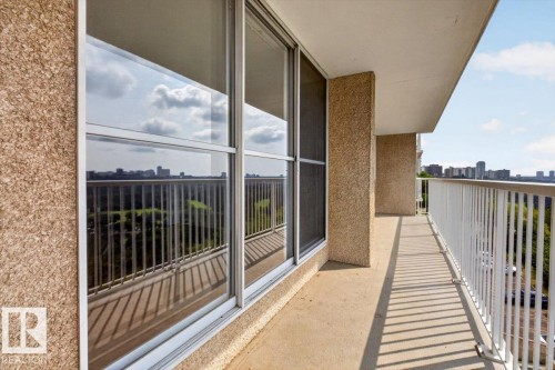 Expansive concrete balcony with white metal railings and large sliding glass doors, offering a panoramic cityscape - #506 12121 Jasper Av Nw, Edmonton, AB - Outdoor With Exterior