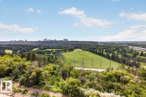 Expansive green space featuring a golf driving range, surrounding mature trees, and a distant city skyline - #506 12121 Jasper Av Nw, Edmonton, AB - Outdoor With View