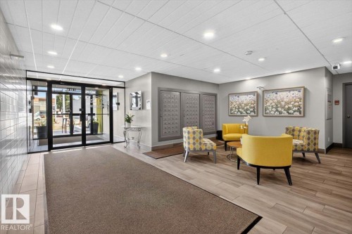 Lobby area featuring glass entry doors, recessed lighting, wood-finish flooring, and wall-mounted mailboxes - #506 12121 Jasper Av Nw, Edmonton, AB - Indoor Photo Showing Other Room