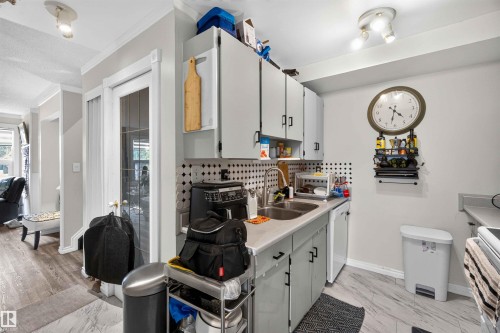 Kitchen area with light gray cabinetry, a dual basin stainless steel sink, and a black and white patterned backsplash - 17127 109 Street Nw, Edmonton, AB - Indoor Photo Showing Kitchen With Double Sink